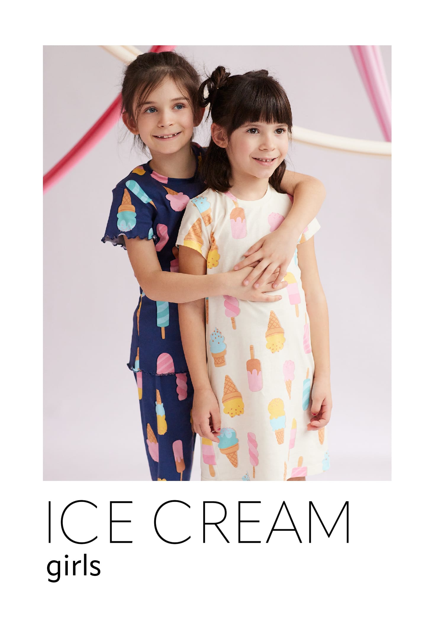 Dve devojčice stoje zagrljene u beloj spavaćici i plavoj pidžami na kratak rukav sa motivima sladoleda