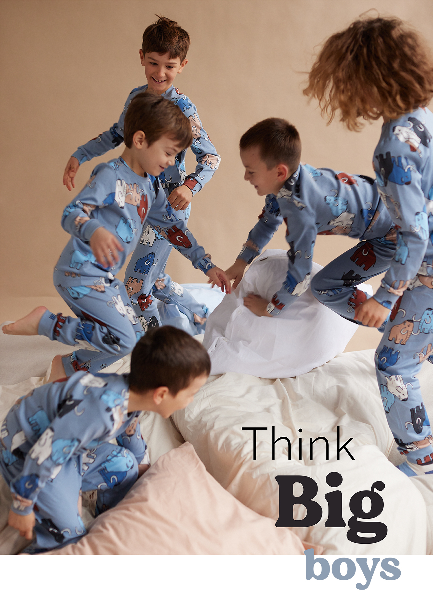 Pet dečaka u plavim pidžamama na dug rukav sa motivom slonova trči po krevetu