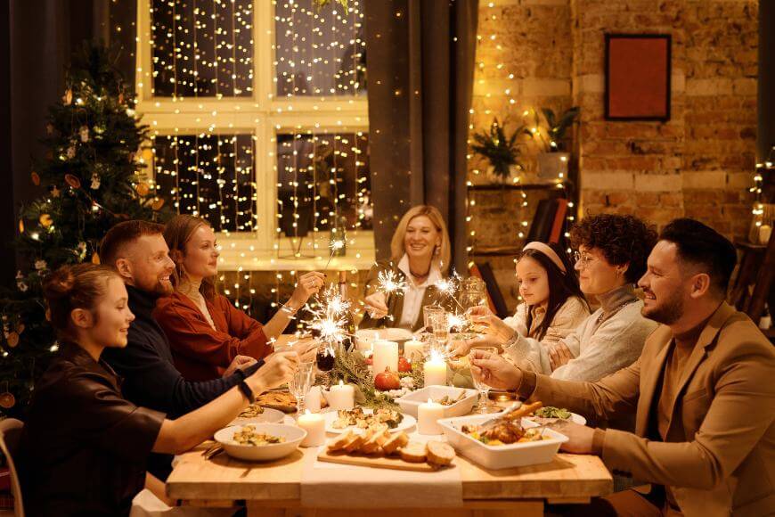 Porodica sedi za stolom sa hranom i drži prskalice