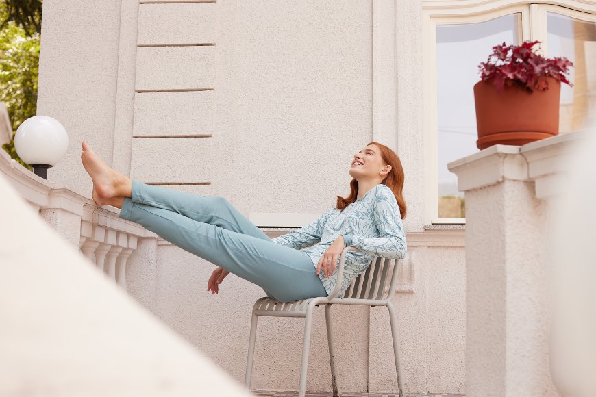 Žena ispruženih nogu sedi na terasi